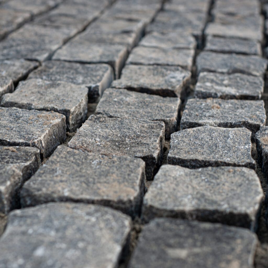 Detailed view of a granite cobblestone street, highlighting the unique shapes and patterns of the cobbles.